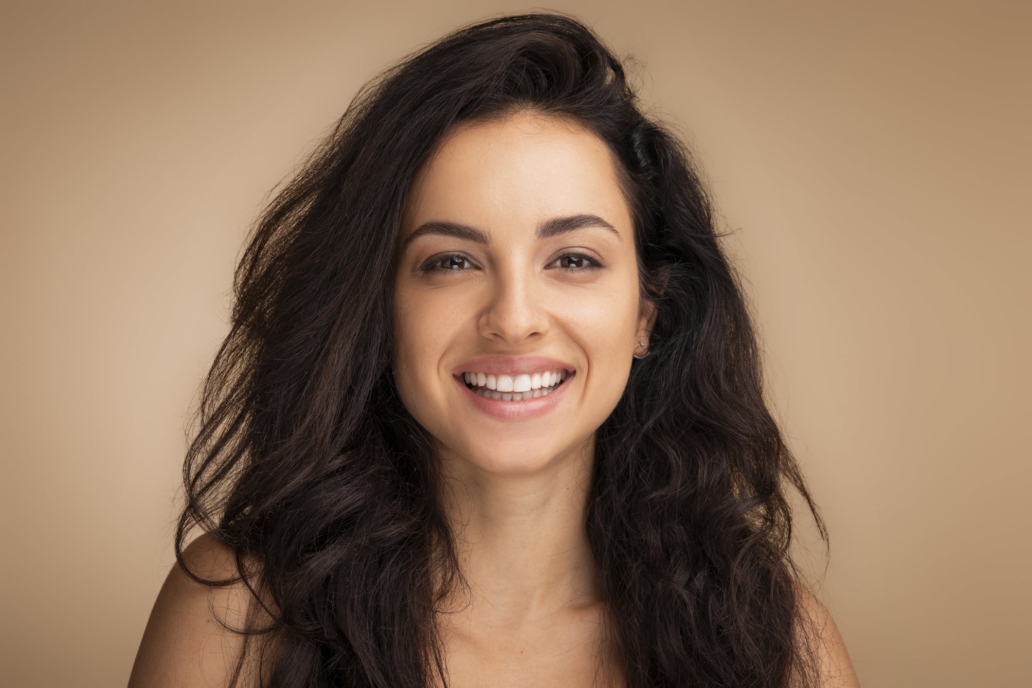 Graceful brunette woman showcasing millennial beauty trends Woman smiling looking refreshed after a deep plane facelift in Newport Beach, CA