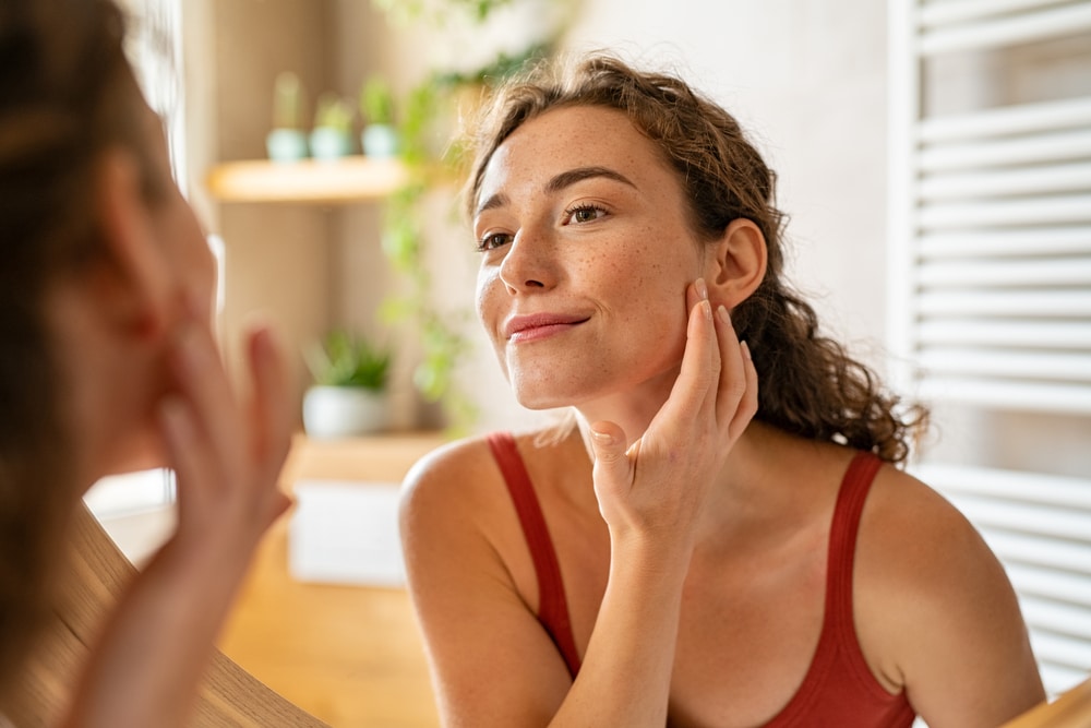 Woman looking in the mirror at her face after a facelift in Newport Beach, CA Woman looking in the mirror at her face after a facelift in Newport Beach, CA