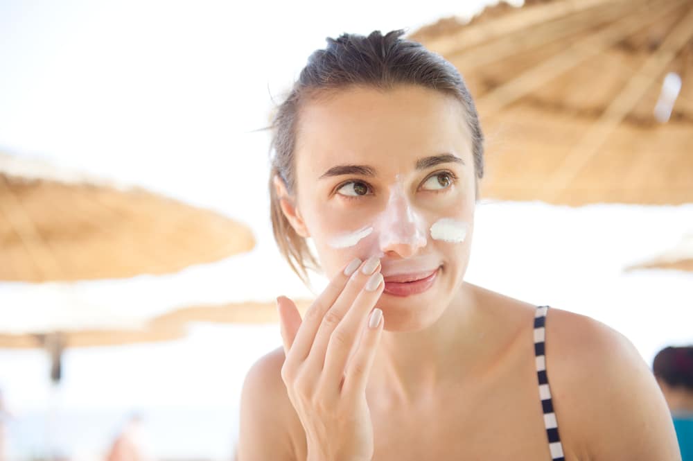 Woman putting on sunscreen to protect her skin from the sun in Newport Beach, CA